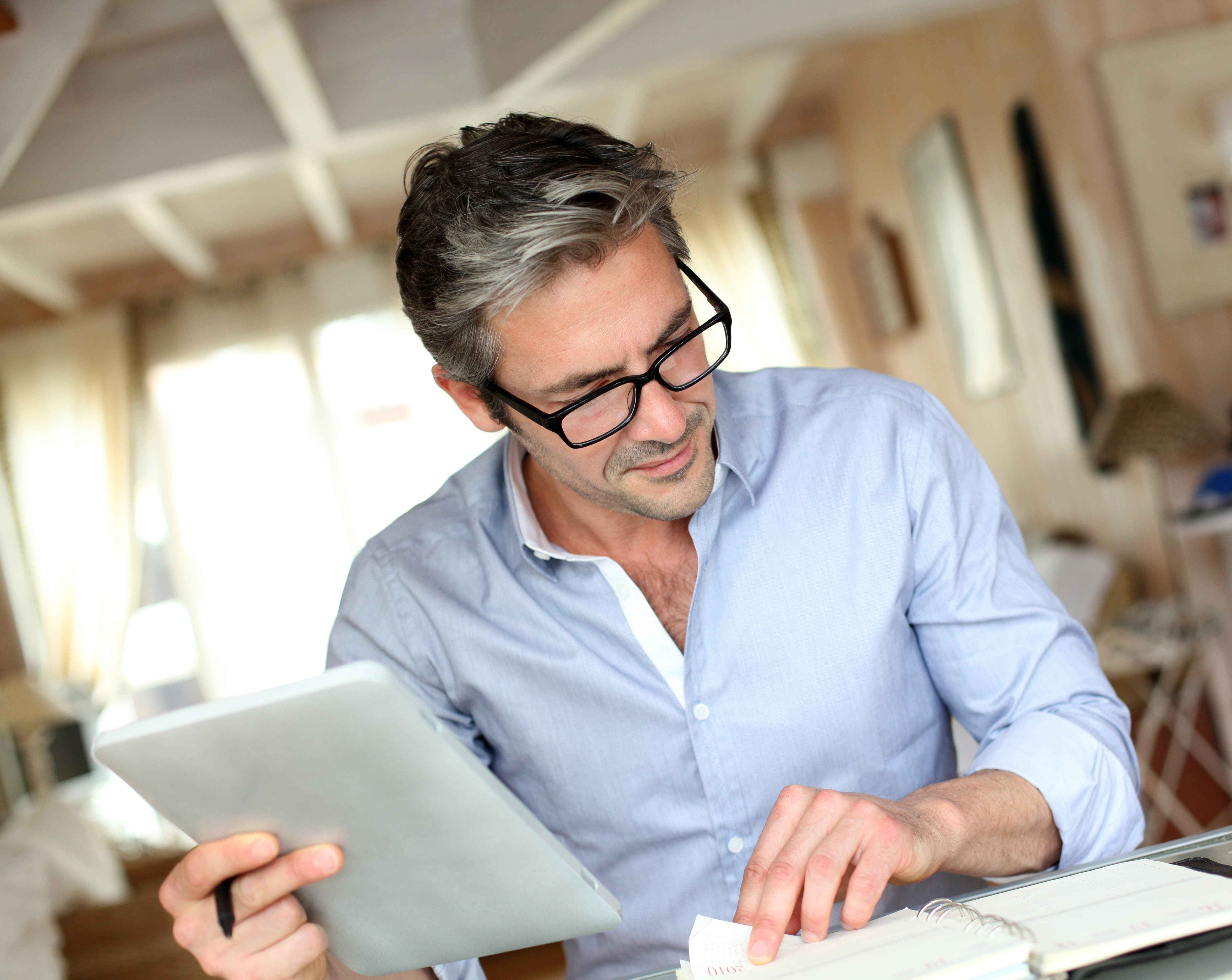 Older businessman working with paperwork and tablet