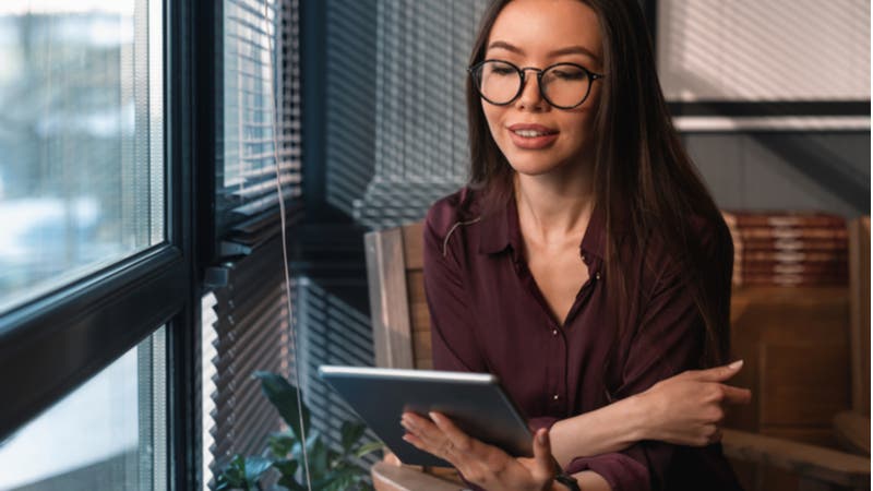 Young woman with glasses reading on tablet