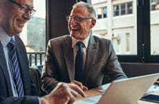 Two older successful businessman laugh during cafe business meeting