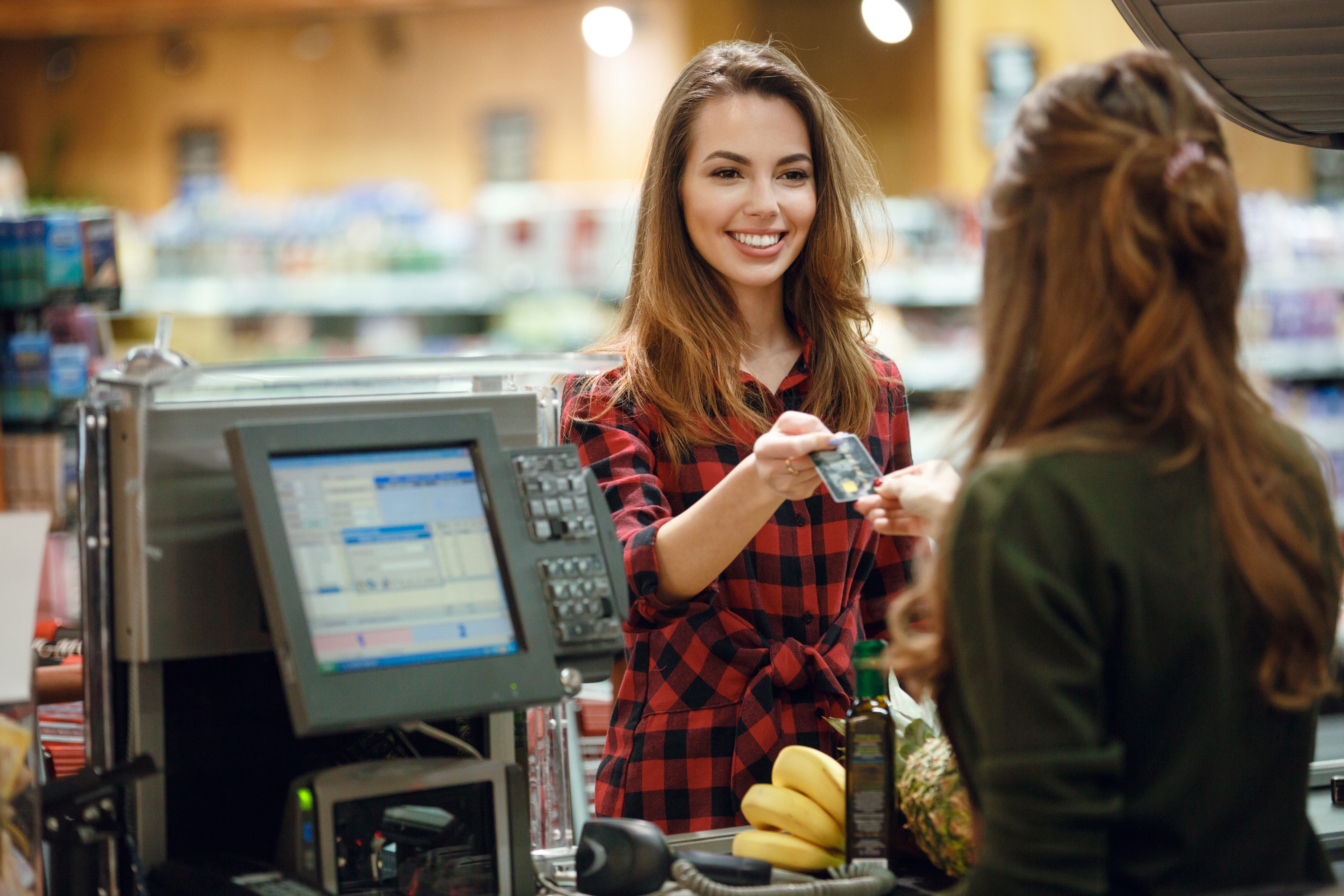 young woman pays for groceries with credit card