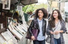Two female friends browse books at an outdoor stand