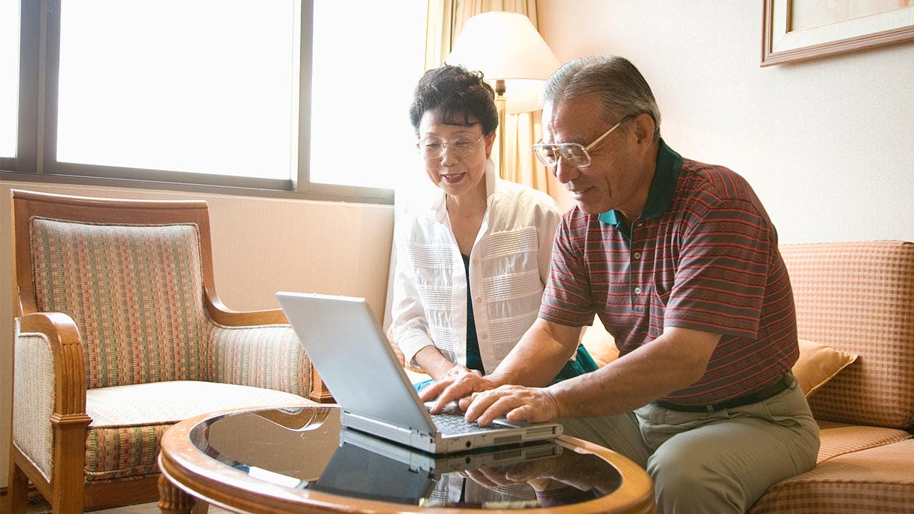 Senior couple using laptop in their living room