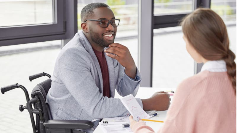 Man in wheelchair discussing paperwork with colleague