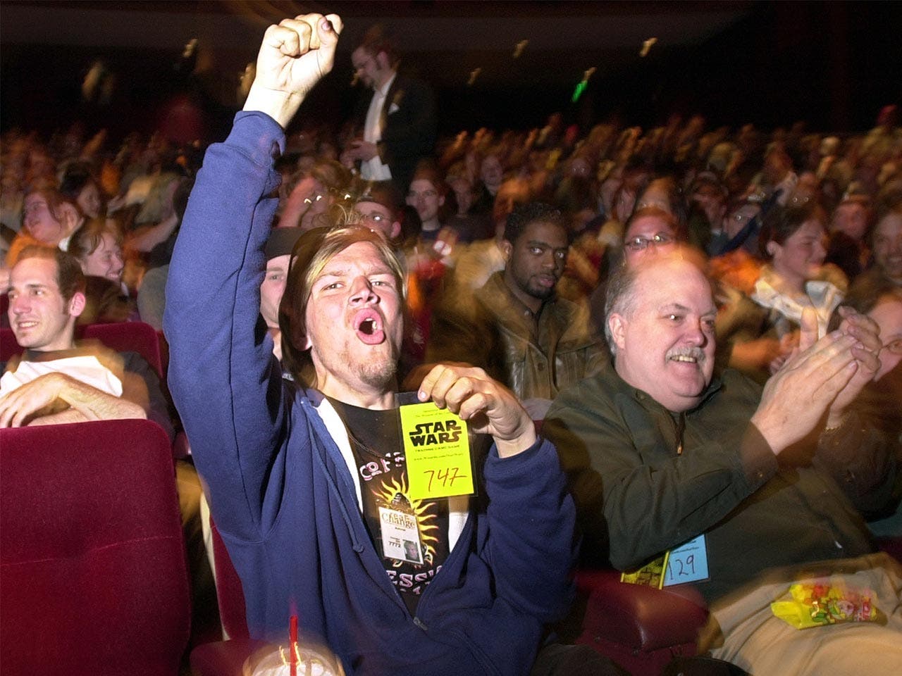 Fan cheering at movie premiere while holding up his numbered ticket