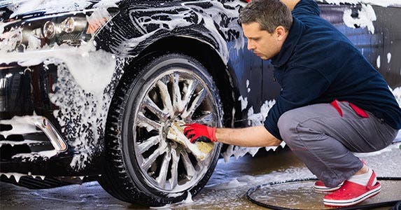 Man washing his car, detailing the tire rims