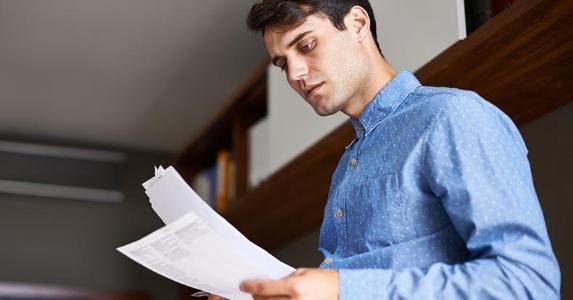 Why $9,000 car loan is more than the sale price Man looking at his bills | PeopleImages/DigitalVision/Getty Images