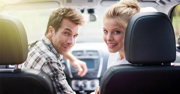 title here Couple seated in front seat of car, looking back © Jack Frog/Shutterstock.com
