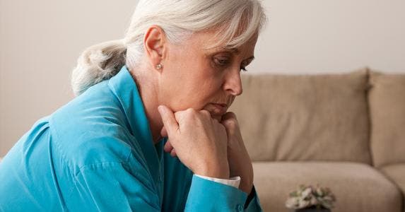 Sad senior woman sitting on couch © Tetra Images/Corbis