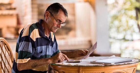 title here Older man doing paperwork | skynesher/Getty Images
