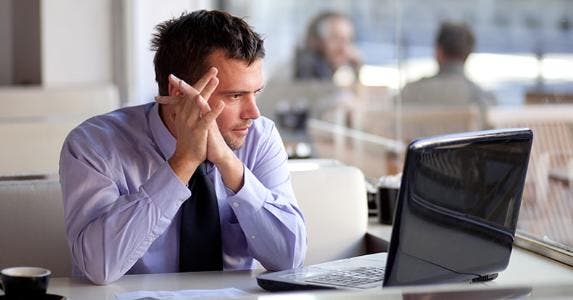 Businessman using laptop in coffee shop © Peter Bernik/Shutterstock.com