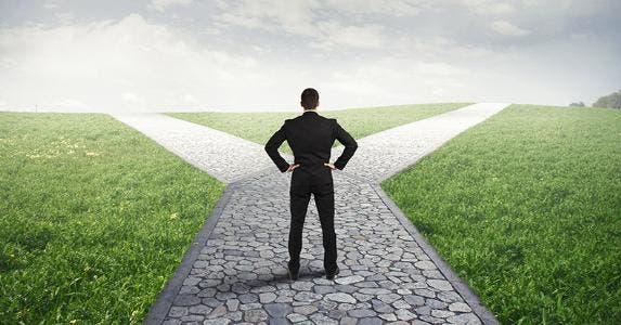 Man standing at fork in road © alphaspirit/Shutterstock.com