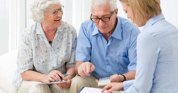 Senior couple holding calculator meeting with adviser