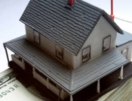 Miniature house on top of money bill