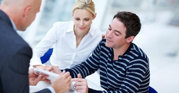 Couple reading documents held by adviser © iStock