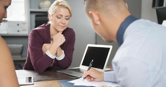 Survey: Millions consider taking out a personal loan Woman watching man write on paper | Compassionate Eye Foundation/DigitalVision/Getty Images
