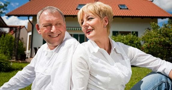 Hidden costs of downsizing a home in retirement Couple sitting outside house / Kzenon - Fotolia