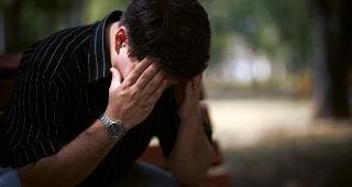 Depressed man sitting outside © luxorphoto/Shutterstock.com