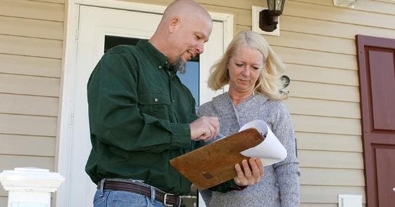Man reviewing clipboard information with woman
