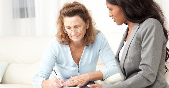 Adviser helping woman sign forms © iStock