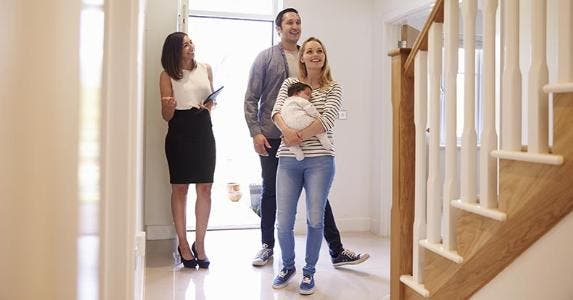 Young couple with infant foyer checking out a house with real estate agent | Monkey Business Images/Shutterstock.com