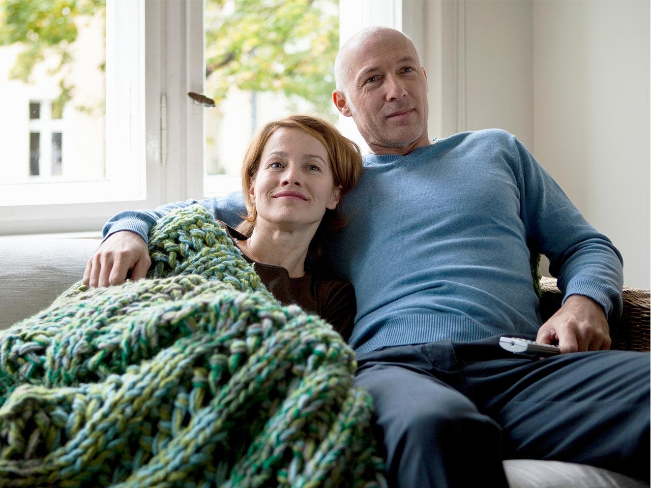 Couple cuddling on the couch under a blanket