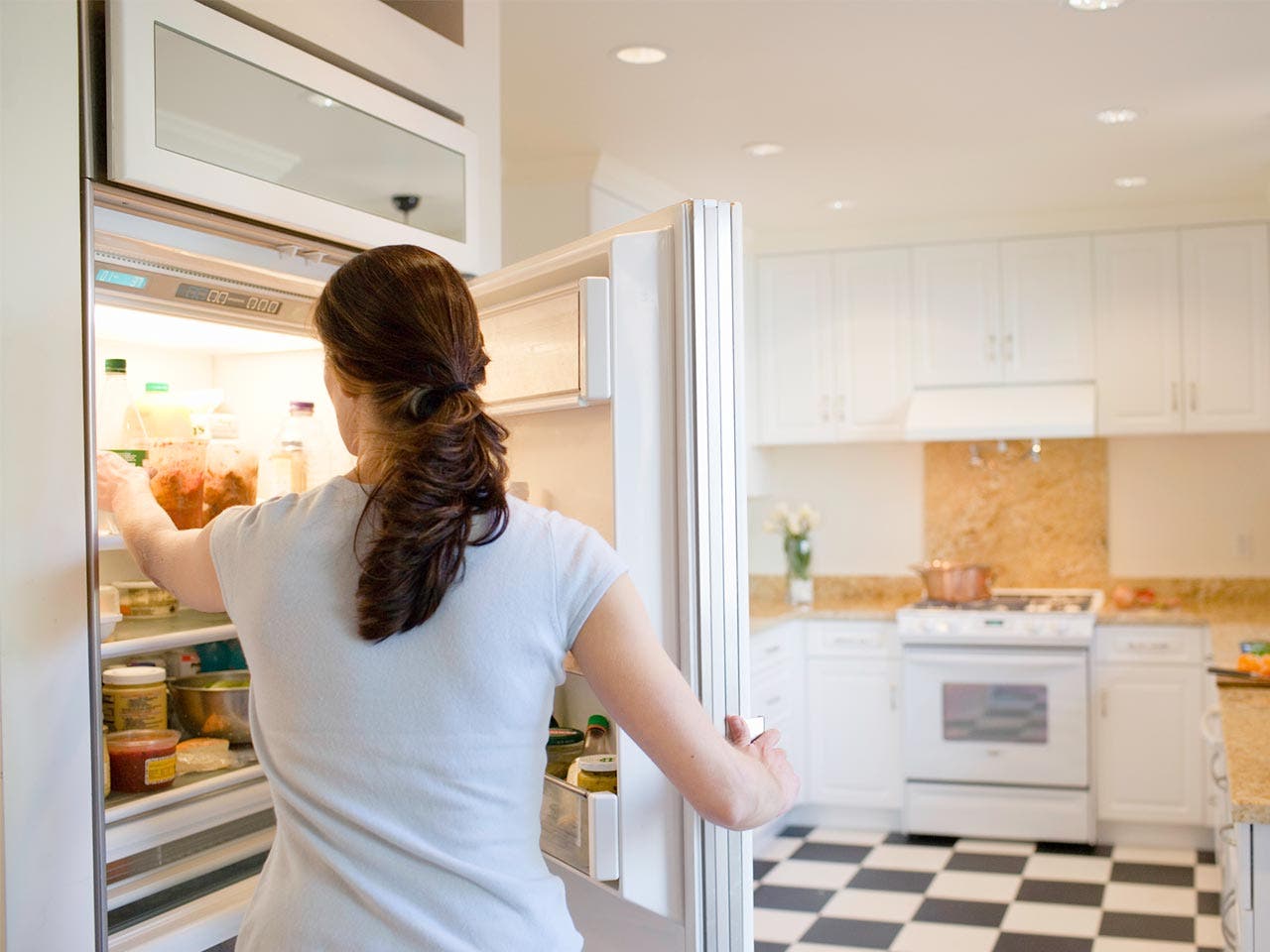 Woman reaching inside her refrigerator