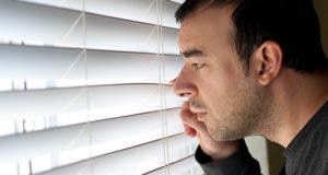 Man peeking through windowblinds © ARENA Creative/Shutterstock.com