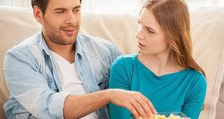 Man stealing popcorn from bowl © g-stockstudio/Shutterstock.com