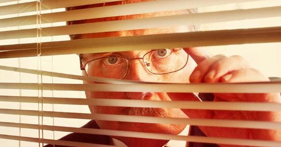 Man looking through window blinds © Suzanne Tucker/Shutterstock.com