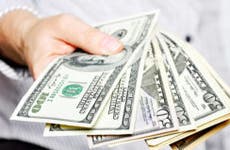 Woman holding fan of $100 and $50 bills
