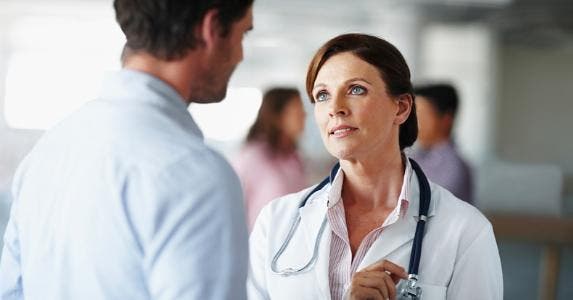 Doctor talking to man in hallway © iStock