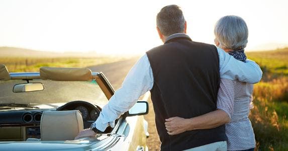 Mature couple standing next to a convertible car, enjoying the scenery © iStock