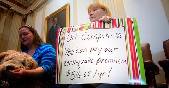 Woman holding sign protesting oil companies in Oklahoma State Capital | J Pat Carter/Getty Images
