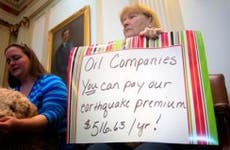 Woman holding sign protesting oil companies in Oklahoma State Capital | J Pat Carter/Getty Images