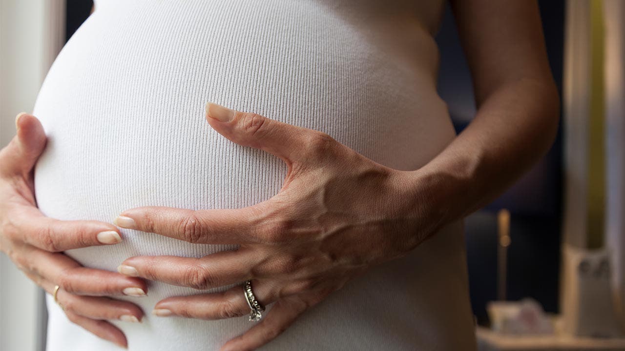 Pregnant woman with her hands on her stomach