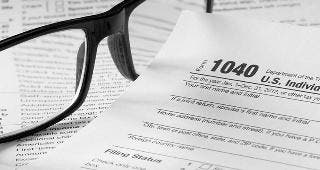 Form 1040 with glasses and pen © topseller/Shutterstock.com