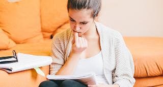 Young woman doing paperwork in living room © Peter Bernik/Shutterstock.com