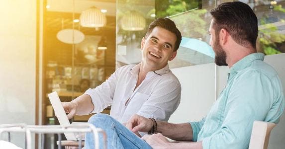Tax costs for poorly timed stock transactions Two men sitting outside, laughing | Vasin Lee/Shutterstock.com