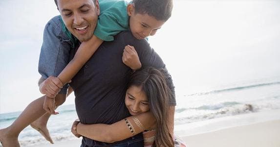 Make sure your children are a tax credit to you Dad horsing around with son and daughter in the beach | Hero Images/Getty Images