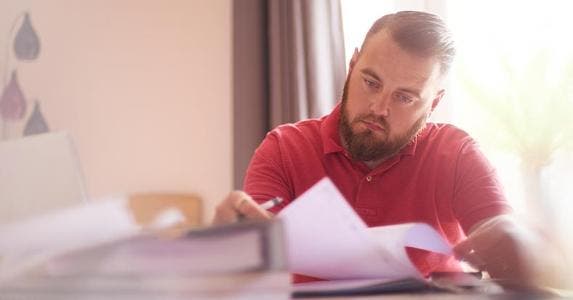 Haven't filed a tax return in years. Now what? Man in red shirt reading letter | Martin Prescott/Getty Images