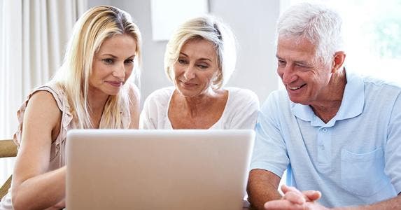 Adult daughter showing computer screen to senior parents © iStock