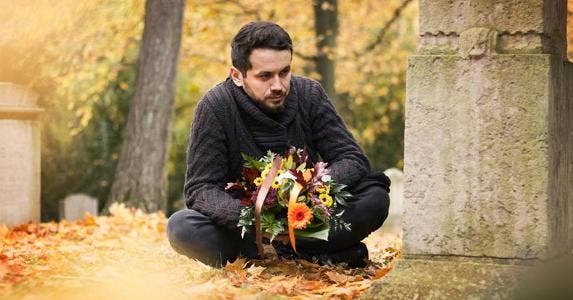 How foreigners pay tax on rental income property Man mourning loved one at graveyard | ajkkafe/Getty Images