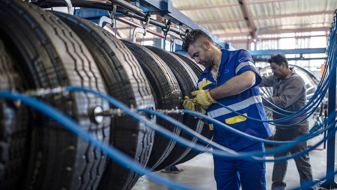 Men inflating car tires in auto shop