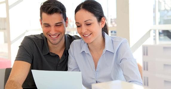Smiling young couple holding a paper © goodluz - Fotolia.com