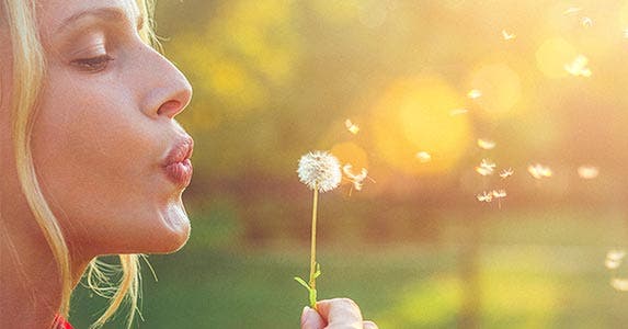 Woman blowing a dandelion
