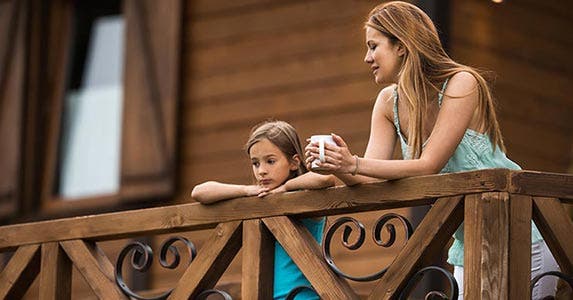 Mother and daughter talking outside on house deck