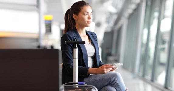 Best and worst frequent flier programs Young woman sitting in an airport waiting to board a plane © Maridav/Shutterstock.com