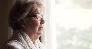 Senior woman standing by window © Nadino/Shutterstock.com