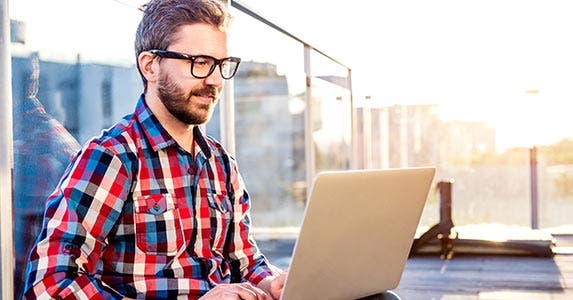 Young man wearing glasses and looking at laptop