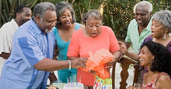 Woman opening birthday gift as family is watching